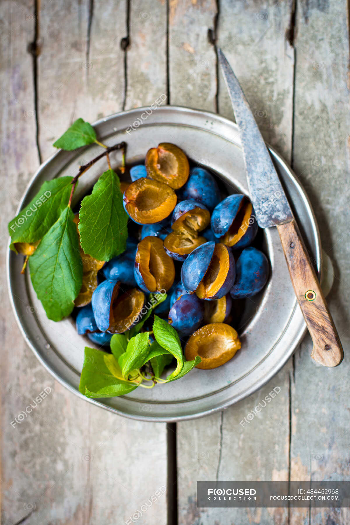 damsons-with-leaves-on-a-pewter-plate-type-view-stock-photo