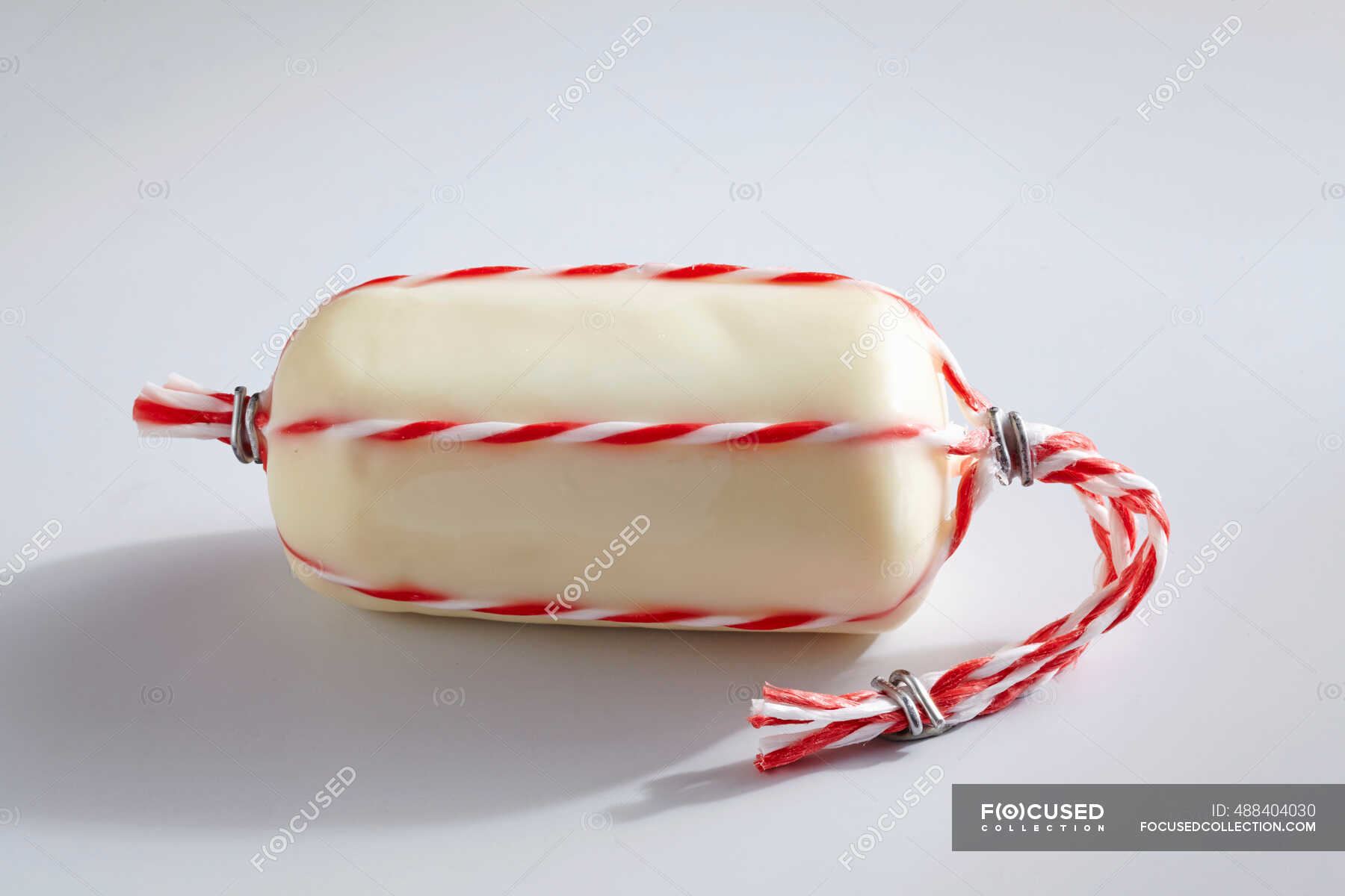 Provolone Topolino cheese wrapped in wax with string — raw, deserted