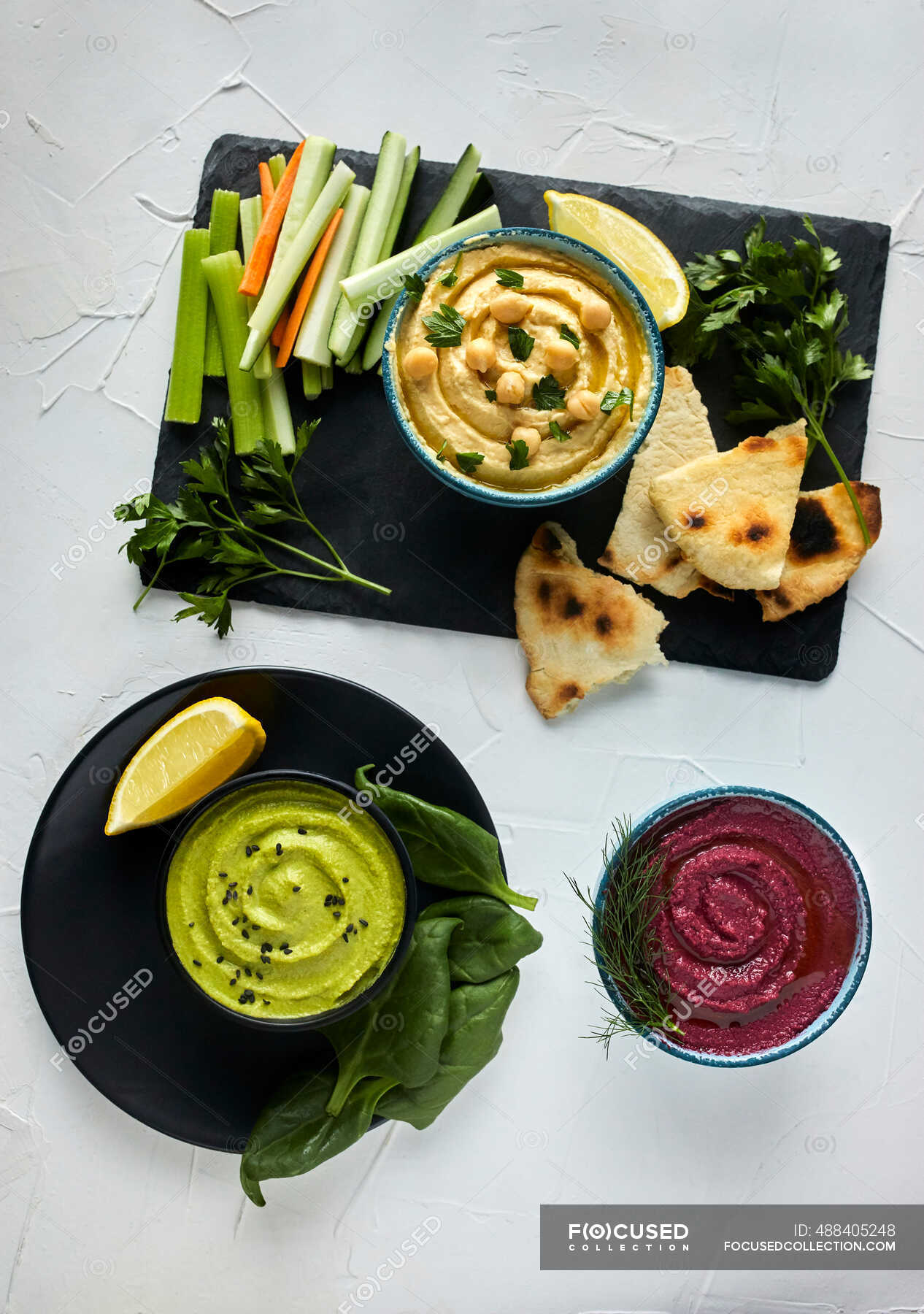 Various types of hummus served with fresh vegetables and pita bread ...