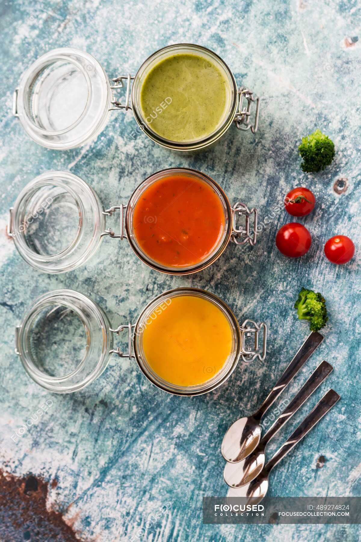 Various colorful soups in glass jars, broccoli soup, tomato soup
