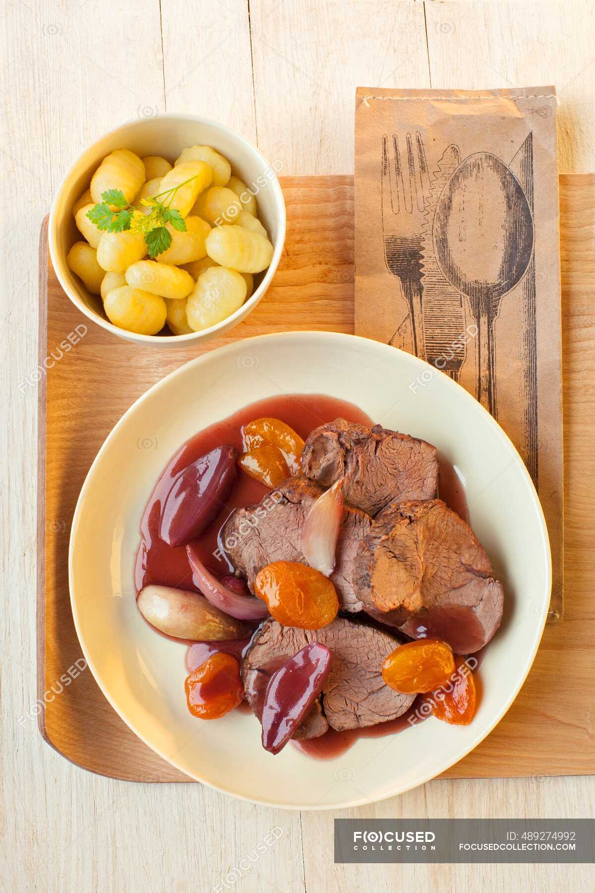 Roast beef with apricots, potatoes and shallots — food, above Stock Photo 489274992
