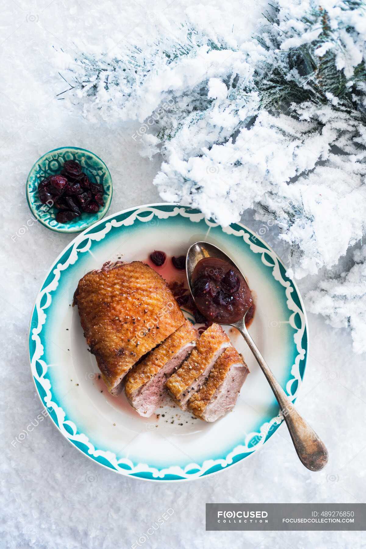 Duck breast with cranberry sauce on a plate in the snow at Christmas ...