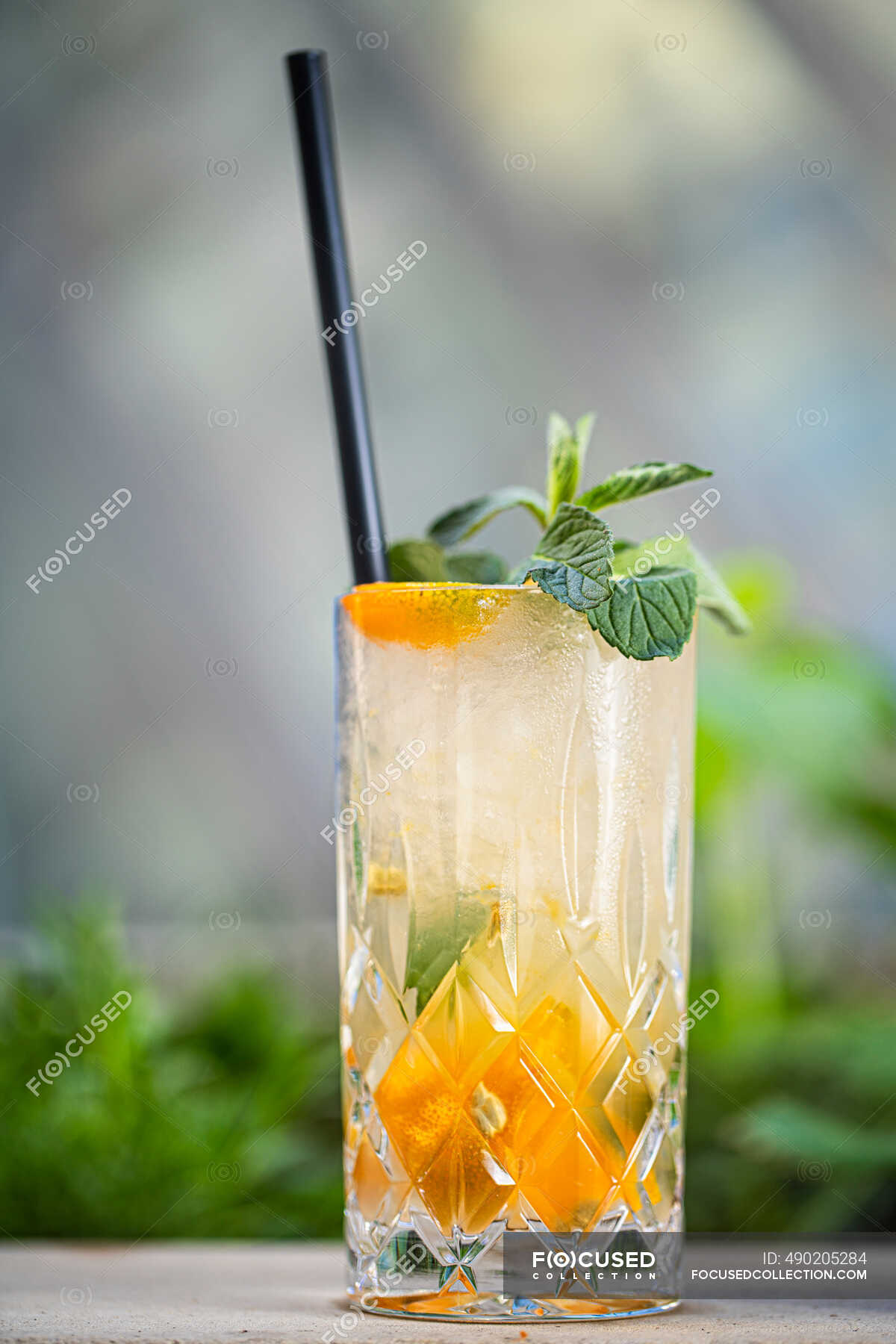 Cocktail with gin, almond syrup, lime juice, kumquats and mint in glass