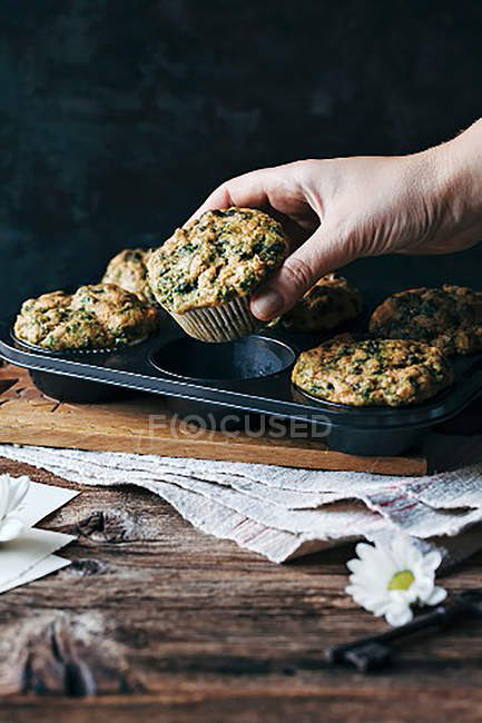 Hand holding vegetable cake wrapped in paper over black tray on table — Stock Photo