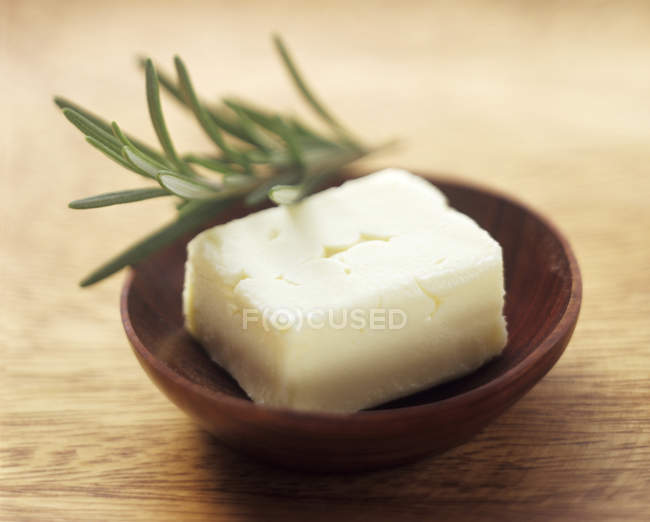 Vue rapprochée du beurre frais dans un bol en bois avec romarin — Photo de stock