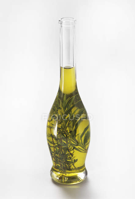 Vista de primer plano del aceite infundido de hierbas en botella de vidrio - foto de stock