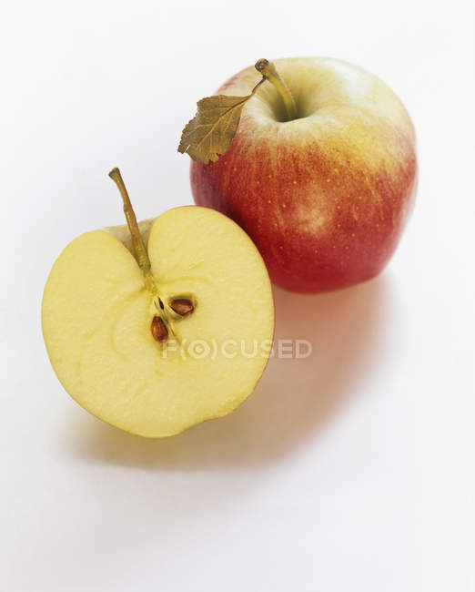 Manzanas Braeburn enteras y cortadas a la mitad - foto de stock