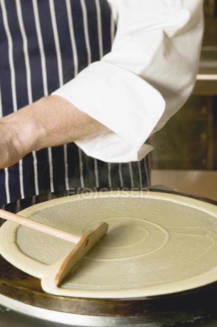 Vue recadrée d'une personne faisant frire une crêpe sur un fer à crêpe — Photo de stock