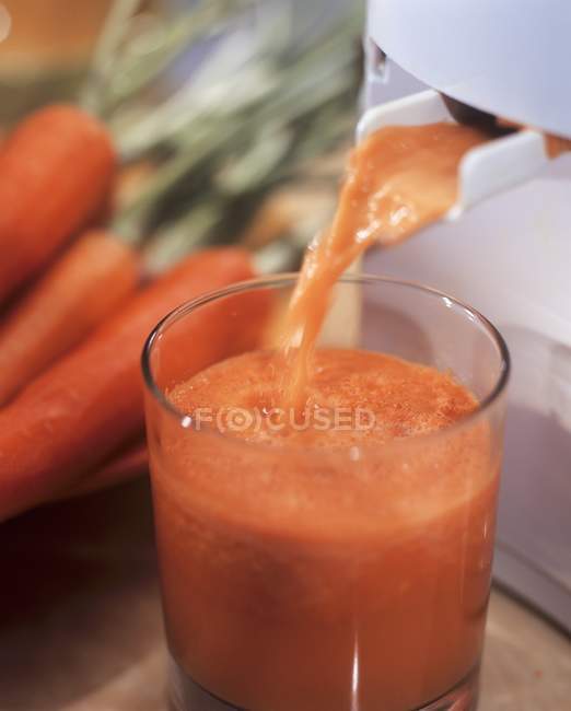 Carrot juice running out of juicer — Stock Photo