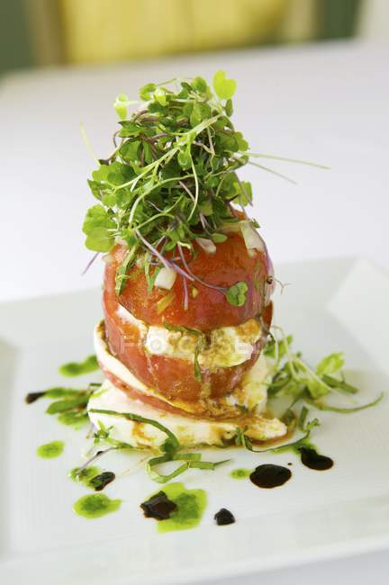Salade de tomate hana et mozzarella de bufflonne avec balsamique, huile de truffe et sel de Kilauea noir sur assiette blanche — Photo de stock