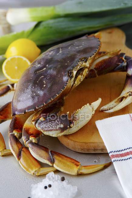 Closeup view of Dungeness crab on wooden board with leek and lemons — Stock Photo