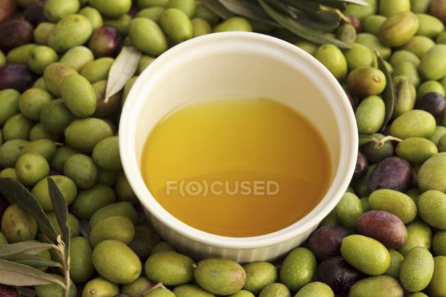 Olio d'oliva spremuto a freddo in ciotola con olive — Foto stock