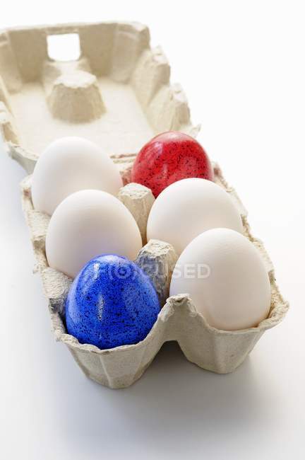 Белые и цветные яйца — стоковое фото
