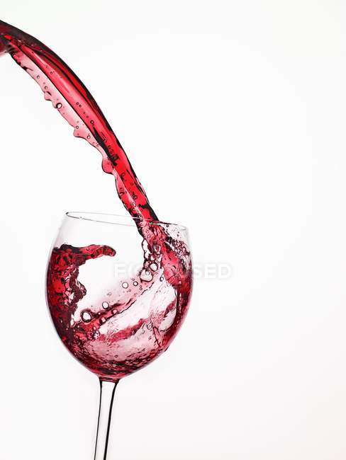 Vinho tinto derramando em um copo — Fotografia de Stock