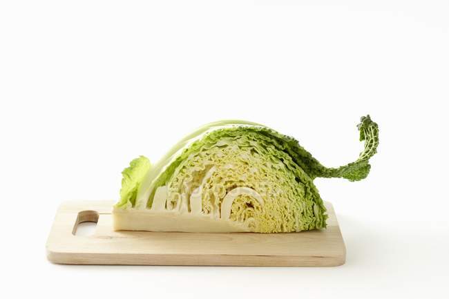 A quarter of a savoy cabage on a chopping board on white background — Stock Photo