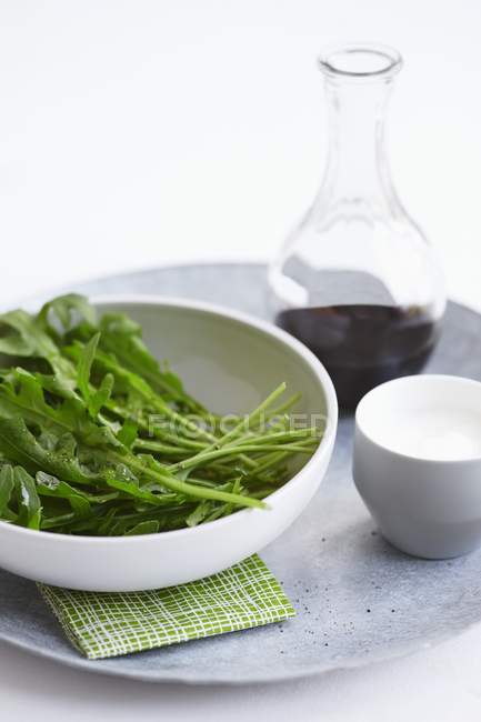 Rocket in bowl with salad dressing — Stock Photo