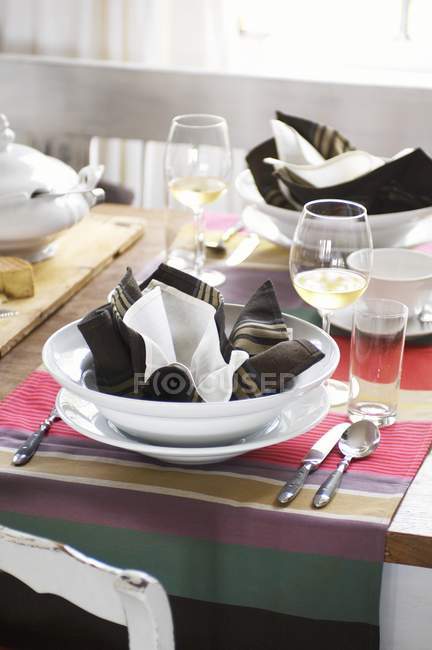 Vista elevada de uma mesa rústica com tigelas de sopa, vinho e guardanapos — Fotografia de Stock