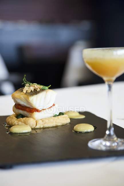 Closeup view of cod fillet with pepper on chickpea puree and a cocktail — Stock Photo