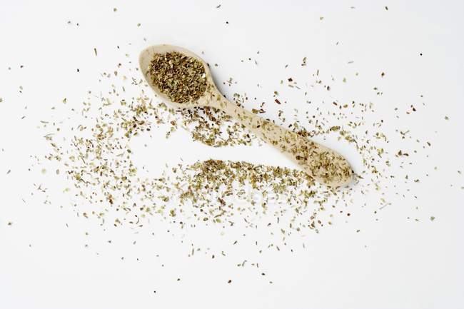 Top view of dried oregano on a spoon and on a white surface — Stock Photo