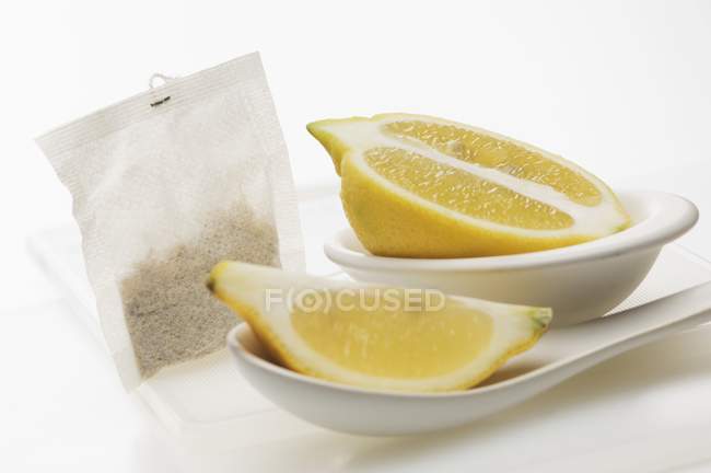 Cunha de limão e metade com saco de chá — Fotografia de Stock