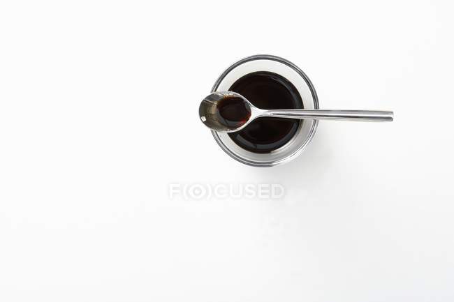 Вид сверху на бальзамический уксус в стеклянной чаше и ложке — стоковое фото