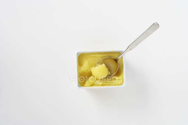 Vista superior de manteiga clarificada em uma tigela com uma colher — Fotografia de Stock