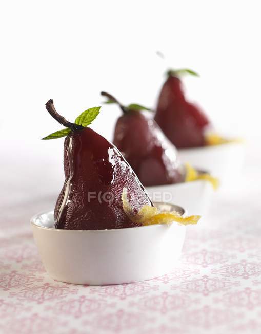Closeup view of poached pears with candied orange peels in white bowls — Stock Photo