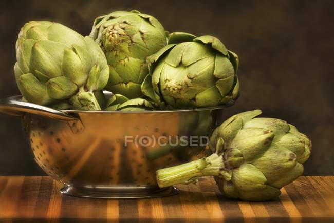 Alcachofas frescas en un colador - foto de stock