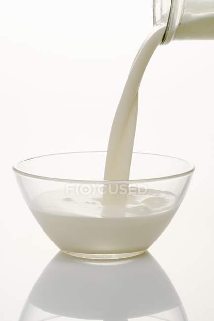 Closeup view of pouring cream to a glass bowl — Stock Photo