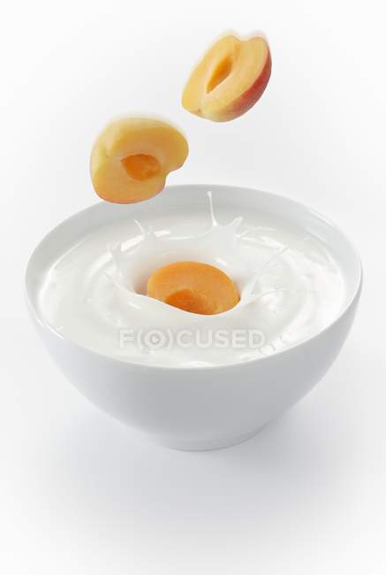 Fresh apricots slices falling in bowl — Stock Photo
