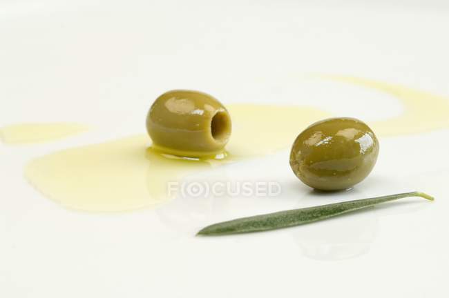 Olive oil with green olives — Stock Photo