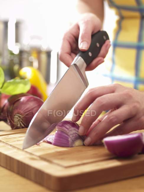 Uma cebola sendo finamente picada por faca na mão — Fotografia de Stock