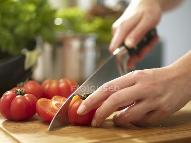 Mãos femininas cortando tomates — Fotografia de Stock