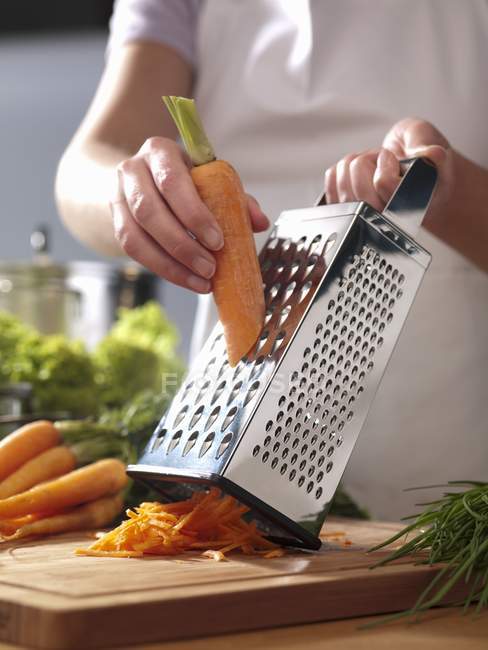 Grating carrots by man — Stock Photo