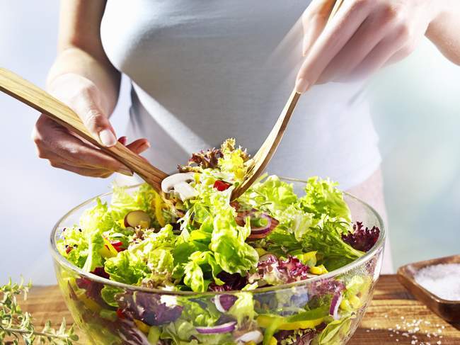 Nahaufnahme abgeschnittene Ansicht einer Frau, die Salat in Schüssel mixt — Stockfoto