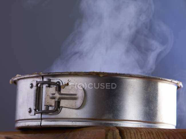 Closeup side view of steaming cake in a cake tin — Stock Photo