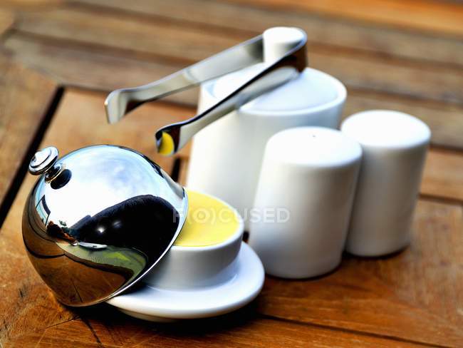 Closeup view of a butter Cloche, salt and pepper shakers and a sugar pot — Stock Photo