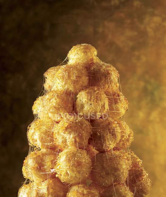 Vista close-up de Croquembouche sobremesa francesa com bolas de pastelaria empilhadas a um cone com fios de caramelo — Fotografia de Stock