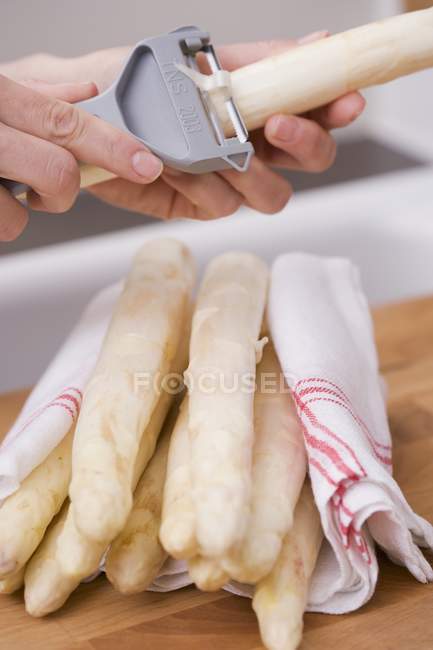 Female hands peeling asparagus — Stock Photo