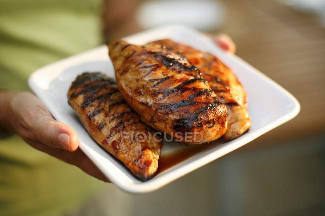 Mulher segurando peitos de frango grelhado — Fotografia de Stock