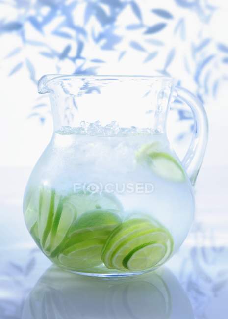Jug of water with limes — Stock Photo
