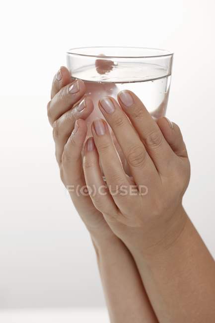 Hände, die ein Glas Wasser halten — Stockfoto