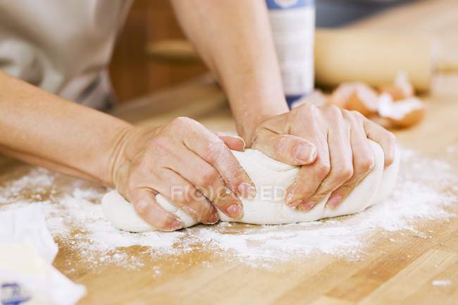 Woman kneading dough on floured counter — Stock Photo