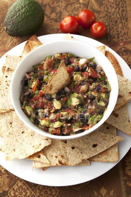 Hausgemachte Guacamole mit Pita-Chips in Schüssel über Teller — Stockfoto