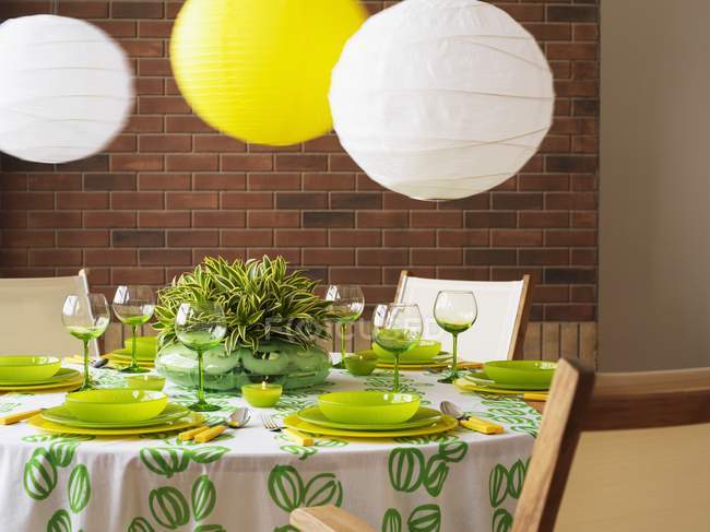 A green and white table set with paper lampshades — Stock Photo