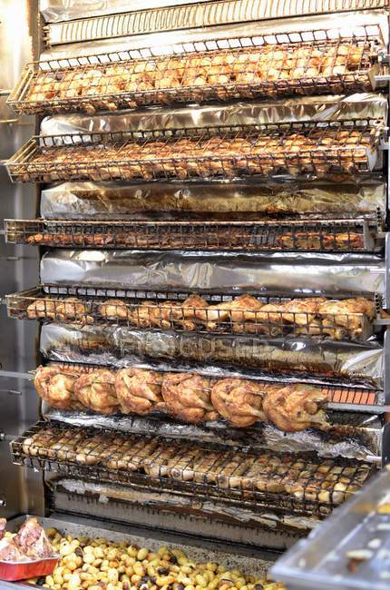 Rotisserie chickens on grill racks in the market — Stock Photo