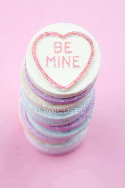 Vista de cerca de caramelos apilados de colores brillantes con palabras Be Mine - foto de stock
