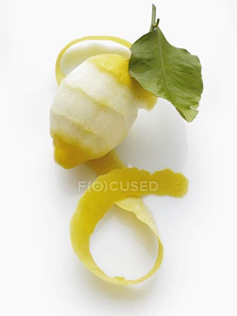 Partially peeled lemon with leaf — Stock Photo