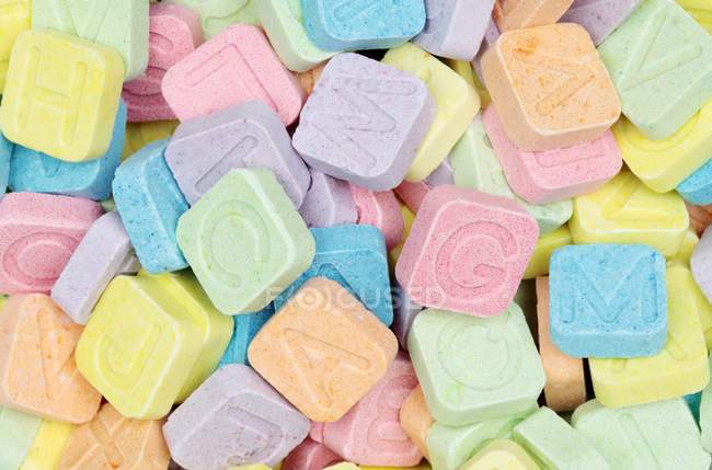 Primo piano vista di caramelle dai colori vivaci con lettere timbrate — Foto stock