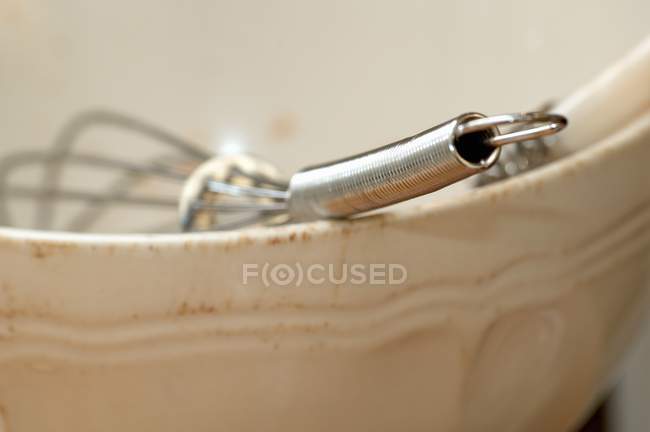 Vista close-up de um batedor em uma tigela de cerâmica — Fotografia de Stock
